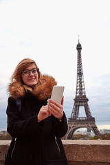 Girl using cellphone with Paris city background and Eiffel tower.
