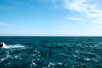 Fototapeta na wymiar Stormy sea, ocean and blue sky background. Horizon of the sea. Beautiful white clouds on the blue sky