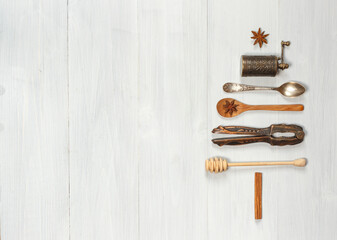 Cutlery, spices and kitchen accessories, the layout in the shape of a Christmas tree on light boards. Top view, horizontal, with space