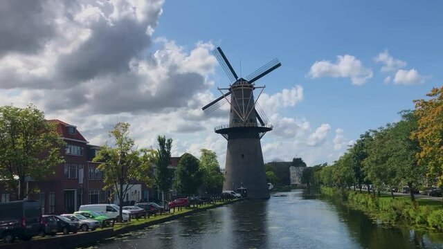 A windmill in Schiedam Netherlands with clouds and beginnings of fall colors.
