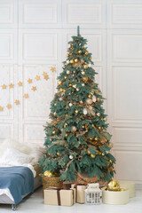 Decorated Christmas tree with gifts underneath. Festive bedroom interior with white walls.