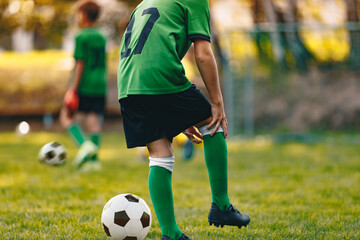 Young soccer player holding injured knee. Soccer boy on training unit. Football player in pain