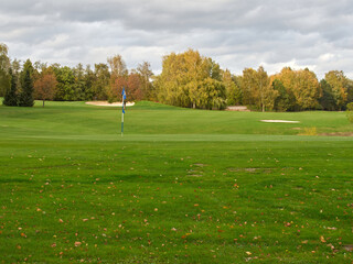 Empty golf course on a cloudy autumn day. Colorful autumn leaves lying on the German golf course in Heiligenhaus in NRW. In the background there are trees with yellow leaves.