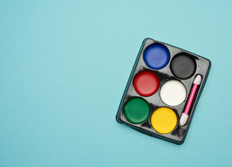 palette with multi-colored makeup paints on a blue background