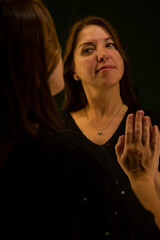 A young woman looks at her reflection in the mirror at home.