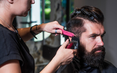 attractive barber making haircut of handsome man in barbershop, hairdressing tools