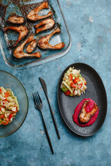 Trout. Baked salmon steaks on a beetroot pillow with vegetable salad, cucumber, tomato, onion, lettuce. Side view, top view.