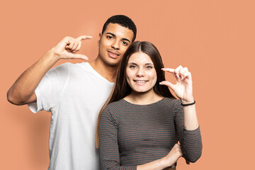 Photo portrait of couple showing small size measures with fingers wearing t-shirts against orange...