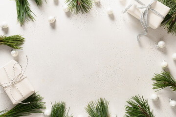 Christmas white frame with gifts, balls, evergreen branches on white background with copy space. Xmas greeting card. Top view.