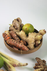 View of Indonesian spices, such as ginger, turmeic, lemon grass, lemon on bamboo oval plate. Dark grainy background.  Raw ingredients.