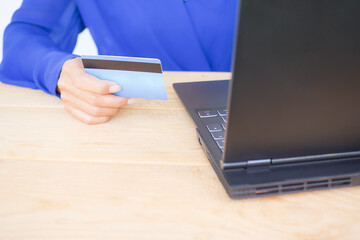 Close up hond holding credit card with laptop on wood background. supporting articles for shopping online, Shopping without cash. business or finance technology concept.