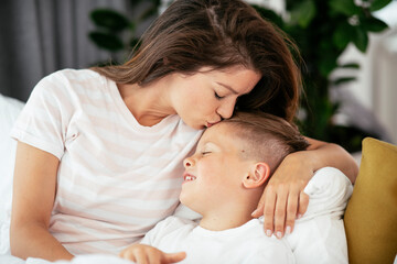 Mother and son enjoying in bed. Happy woman with son relaxing in bed.