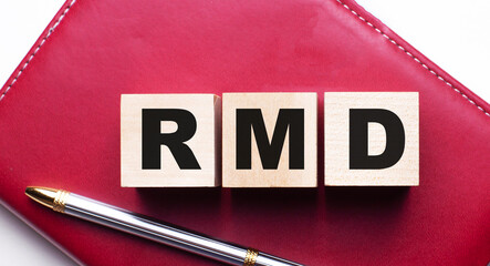 RMD is made up of wooden cubes that stand on a burgundy notebook near the pen. Business concept