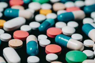 Pharmacy theme. Multicolored Isolated Pills and Capsules on Black Surface. Vitamins, drugs concept. COVID-19, Coronavirus, epidemic
