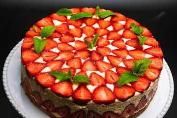 Amazing beautiful hand decorated homemade strawberry Fraisier cake. Tasty, fresh, appetizing dessert close-up with sprigs of mint. Confectionery art, perfectionism in food concept.