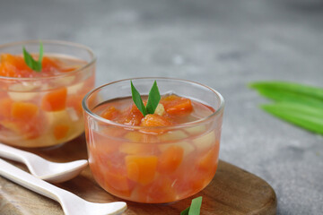 Es Buah, Indonesian traditional cocktail fruits popular during Ramadan month, made from sugar syrup, papaya, pineapple and other fruits. Served on clear glass on, grey wooden background. Copy space.