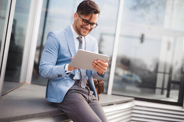Young modern businessman using tablet on pause