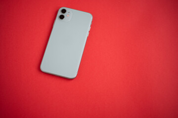 A modern mint-colored smartphone on a red background. Modern and minimalistic concept.