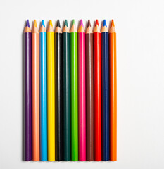 Buntstifte in verschiedene Farben aufgereiht auf weißen Hintergrund