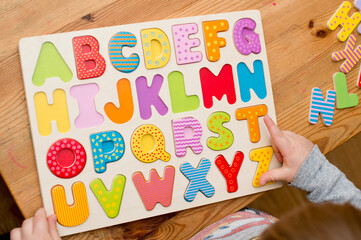 Baby early learning. Wooden letters of the alphabet. Children reading puzzle. Kids educational game, match the right place. Teaching develop intellectual kid game board.
