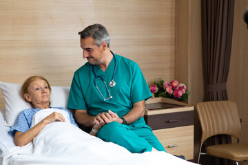 Close up of male doctor hands holding senior woman patient hand in hospital bed. comforting and...