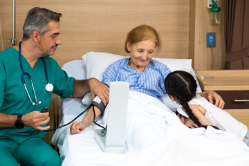 Happy elderly patient lying on hospital bed with grandchild visitor. grandmother and granddaughter...