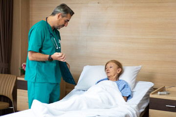 Physician examining senior woman patient in hospital room. Healthcare and medical background concept