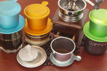 Traditional vietnamese drip coffee, coffee phin, coffee grinder and beans on wooden table
