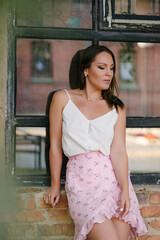 A portrait of a girl who thoughtfully lowered her gaze against the background of an old brick window.