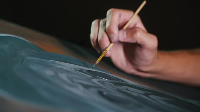Drawing process, close-up of the artist hand drawings with a brush on the canvas in slow motion