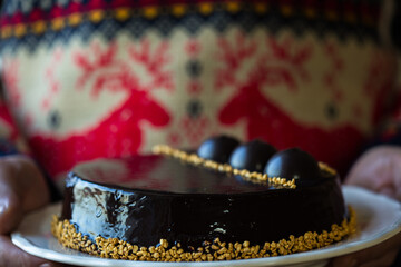 Chocolate Christmas Cake on dark background. Classic chocolate cake with dark chocolate and Christmas lights, sparklers
