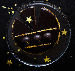 Chocolate Christmas Cake on dark background, top view. Classic chocolate cake with dark chocolate and Christmas lights, sparklers
