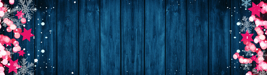 Naklejka premium Christmas / Advent background banner Panorama, card template -Pink stars, bokeh lights, ice crystals and snowy snowflakes, isolated on dark blue wooden bards wall texture wood, with copy space