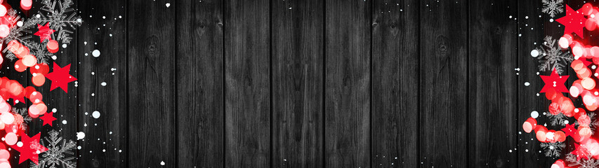 Fototapeta premium Christmas / Advent background banner Panorama, card template -Red stars, bokeh lights, ice crystals and snowy snowflakes, isolated on dark black wooden bards wall texture wood, with copy space
