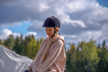Portrait of a girl in a helmet against a cloudy sky.
