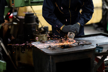 Labor man use Electric wheel grinding on steel structure in factory. Man Worker at industrial factory wearing uniform and hard hats. Engineering and architecture concept