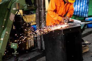 Labor man use Electric wheel grinding on steel structure in factory. Man Worker at industrial factory wearing uniform and hard hats. Engineering and architecture concept