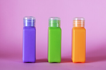Isolated spa cosmetic products, multicolored tubes, on a pink background. Plastic bottle for detergent cleaning agent