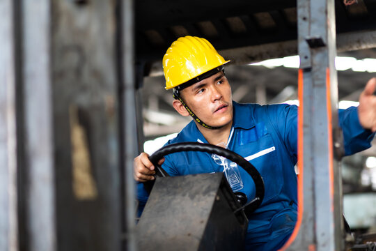 Man At Work. Professional Operation Engineering. Young Asian Worker Forklift Driver Wearing Safety Goggles And Hard Hat Sitting In Vehicle In Warehouse