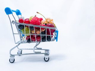 Mini grocery cart filled with fresh vitamin berries isolated on white background