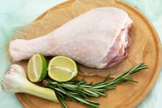 aw leg of turkey cutting board with limes and parsley on a white background, isolate..