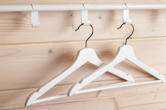 Two white hangers are near blank wooden wall