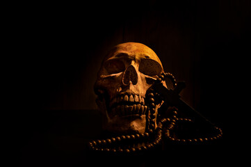 Still life art of a human skull and bead on a black background