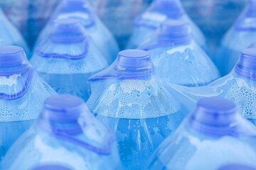 close-up of large blue bottles of drinking water Packed in polyethylene, transparent film in a warehouse in the store.Plastic transparent bottle with blue lid