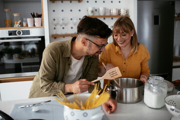 Husband and wife in kitchen. Young couple preparing delicious food at home..