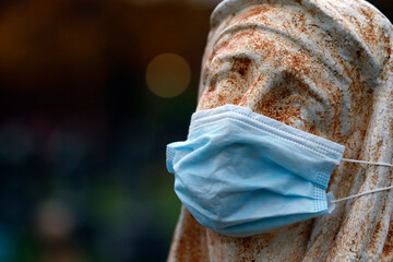 Statue dans un cimetière avec un masque facial jetable pendant la pandémie de Covid-19