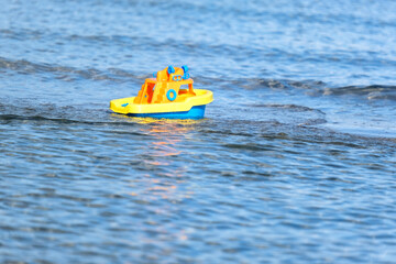 Konzept Urlaub mit Kindern am Meer: Buntes Spielzeugschiff treibt im Meer - selektiver Fokus, viel...