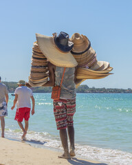 Hat seller walking on the beach.

