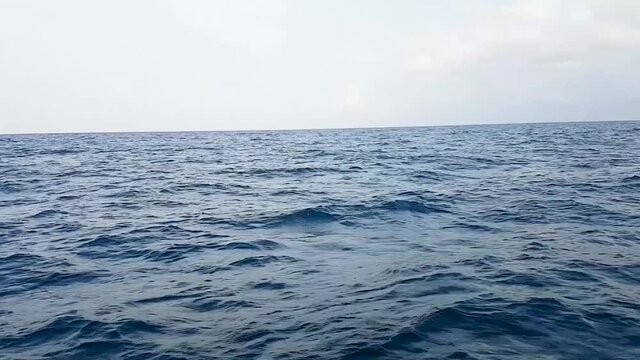 Rough blue sea. Big waves in the open ocean during a storm. Calm weather, cloudy overcast sky.