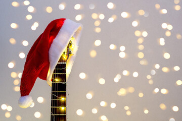 Acoustic Guitar with red Santa hat and light garland. Christmas music song concept with copyspace